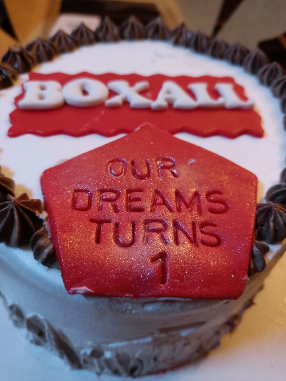 A cake iced with the Boxall logo and the words our dreams turns 1
