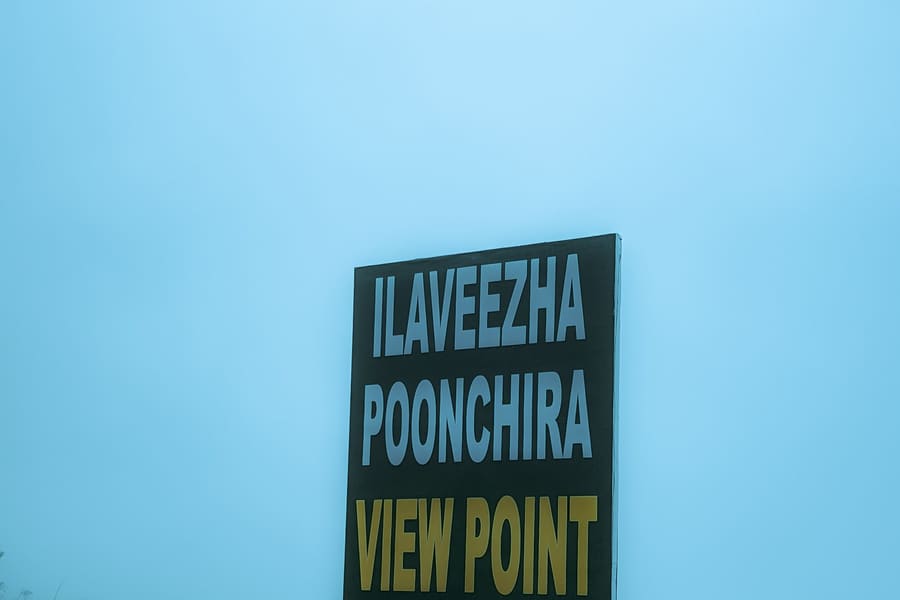 The Ilaveezha Poonchira View Point signboard standing in thick mist